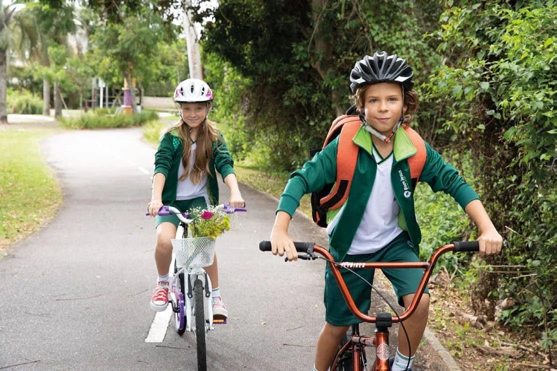 Crianças pedalando em uma ciclovia arborizada do bairro